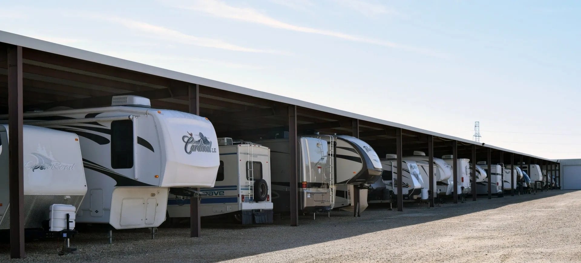 Rows of fifth-wheel trailers parked under the covered storage canopy at Texas RV Center.